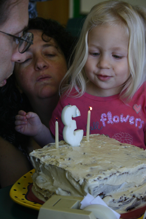 Miriam blowing out her birthday candle with help from mom and dad