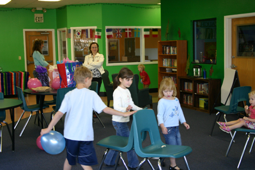 Children playing musical chairs, looking towards front right of room