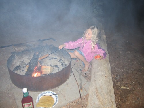 Miriam cooking hot dogs over the campfire